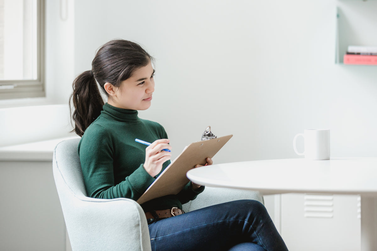 Woman reviewing notes on a clipboard in a calm, bright setting