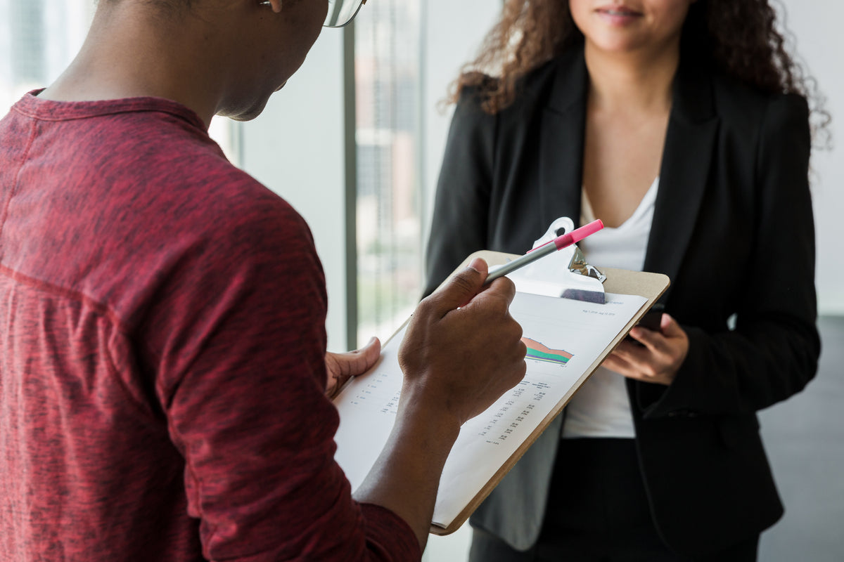 Two professionals reviewing data on a clipboard during a consultation