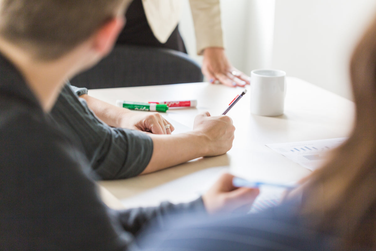 People taking notes and reviewing documents during a consultation